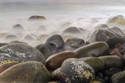 Pebbles at beach against sky