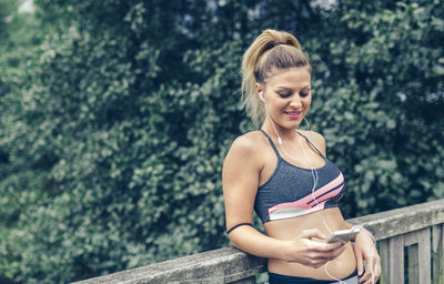 Beautiful smiling young woman using phone on boardwalk