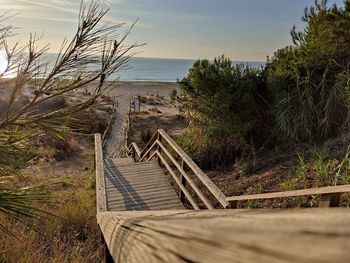 Wooden footbridge on beach against sky