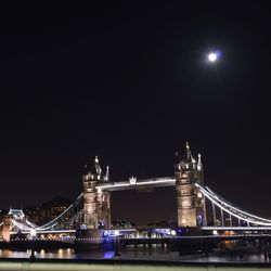 Illuminated bridge over river at night