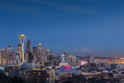 Illuminated cityscape against clear blue sky