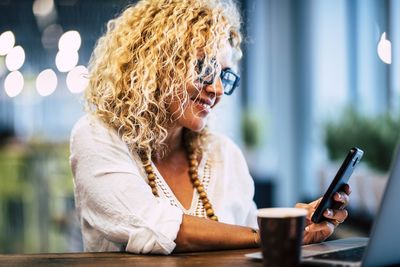 Midsection of woman using mobile phone while sitting on table