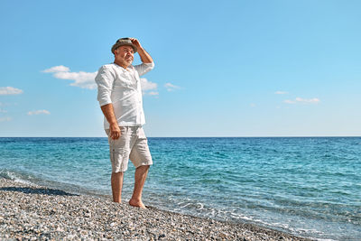 Happy middle-aged bearded man walking along beach. concept of leisure activities, wellness, freedom