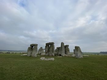 Stone wall on field against cloudy sky