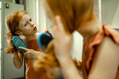 Girl brushing hair in front of mirror