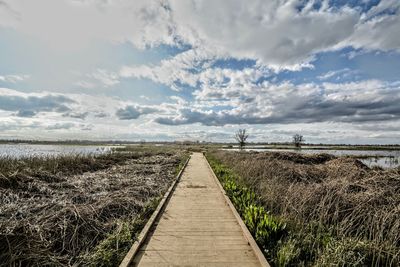 Boardwalk leading towards sea against sky