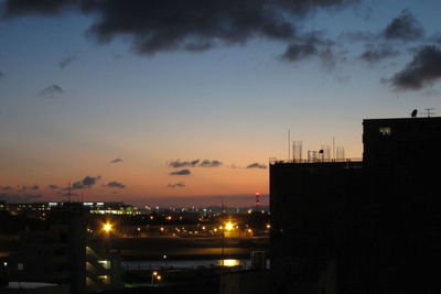 Illuminated cityscape against sky at sunset