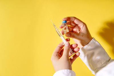 Close-up of person hand holding yellow paper against gray background