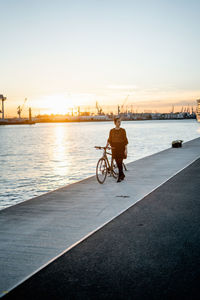 Rear view of man riding bicycle on river in city