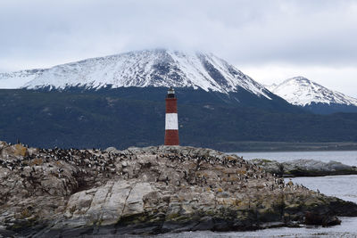 Lighthouse on snow covered mountain against sky