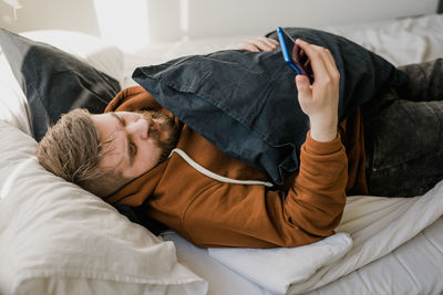 High angle view of man using mobile phone while lying down on sofa at home