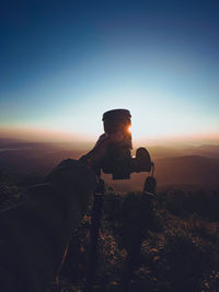 Man on mountain against clear sky during sunset