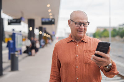 Portrait of young man using mobile phone in city