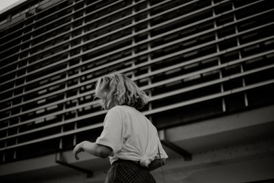 Rear view of woman standing by window