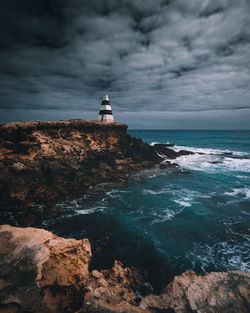 Lighthouse by sea against sky