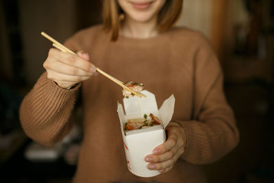 Midsection of woman eating food at home