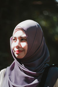 Smiling young woman in headscarf looking away