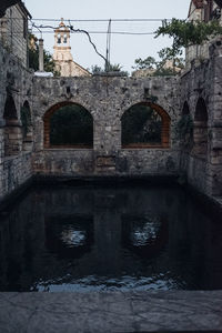 Arch bridge over river against old building