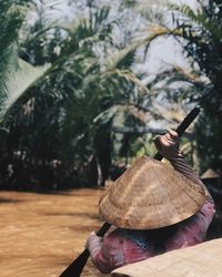 Rear view of woman holding hat on tree