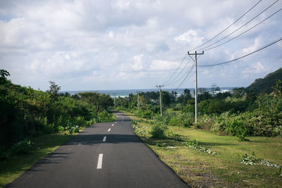 Road by trees against sky