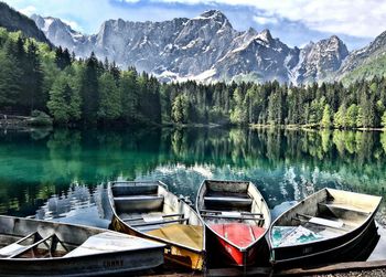 Boats moored on lake against mountains