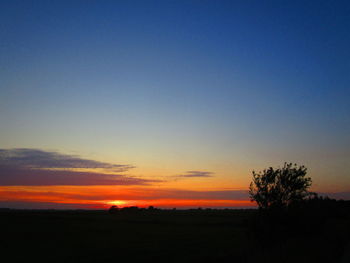 Scenic view of silhouette field against clear sky during sunset