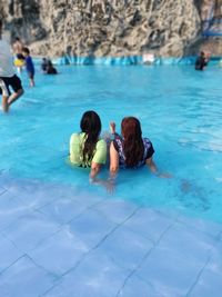Rear view of people sitting in swimming pool