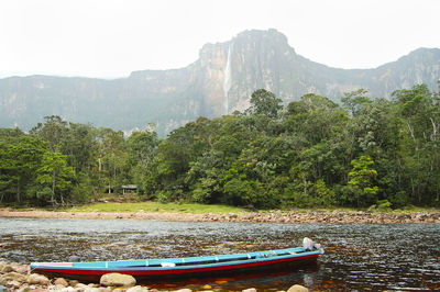 Boats moored in river against mountain