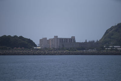 Sea by buildings against clear sky