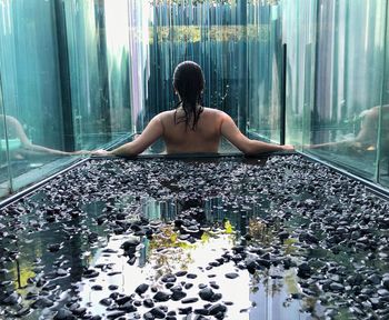 Rear view of woman sitting in swimming pool