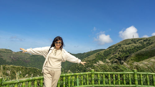 Woman standing by railing against mountain