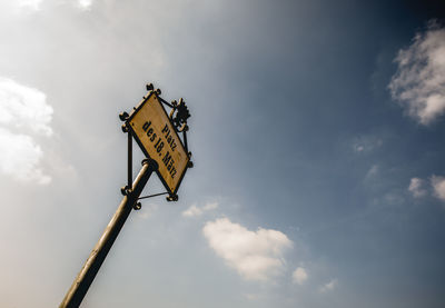 Low angle view of sign board against sky
