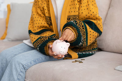 Midsection of woman holding piggy bank on bed at home