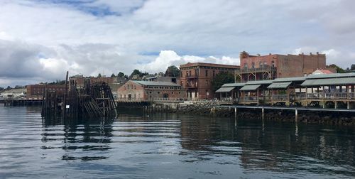 Buildings by river against sky in city