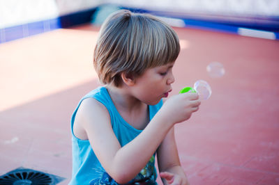 Kid blowing soap bubbles on a terrace.