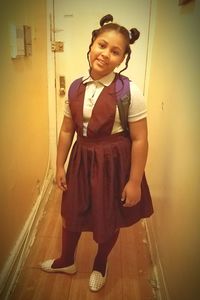 Portrait of young woman standing against wall