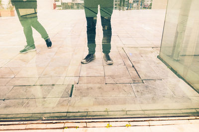 Low section of people standing against glass building