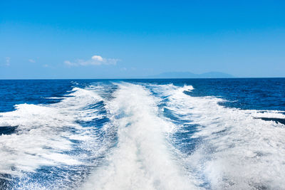 Wave from cruise boat on water surface and horizon with blue sea