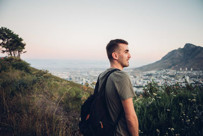 Young man standing on landscape against clear sky