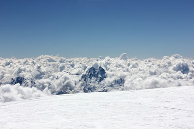 Snow covered landscape against blue sky