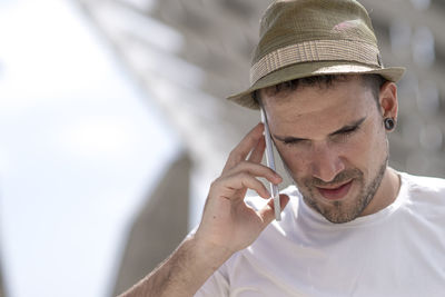 Man wearing hat while answering smart phone