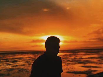 Silhouette man looking at sea during sunset