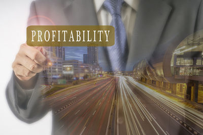 Double exposure image of businessman with profitability text and illuminated city