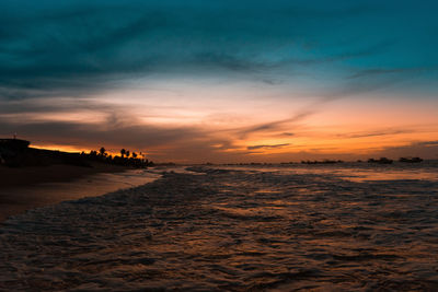 Scenic view of sea against dramatic sky during sunset