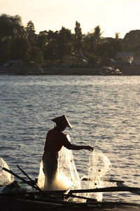 Man sitting on boat in lake against sky