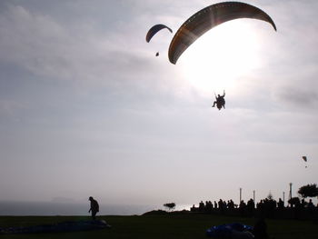 People paragliding against sky during sunset