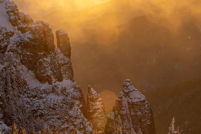 Rock formations against mountain during sunset