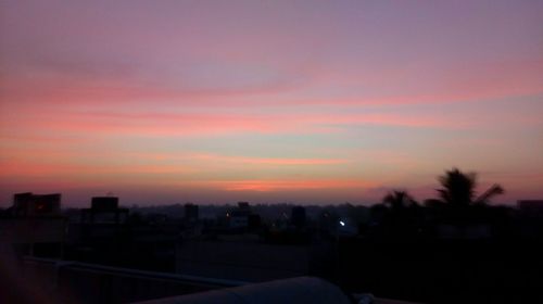 Silhouette cityscape against sky at sunset