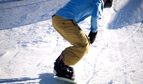 Low section of man snowboarding on field