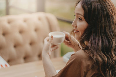 Smiling woman drinking coffee in cafe
